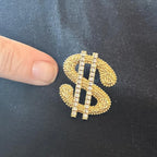 Jakris gold-tone dollar sign brooch with sparkling crystal accents pinned on black fabric