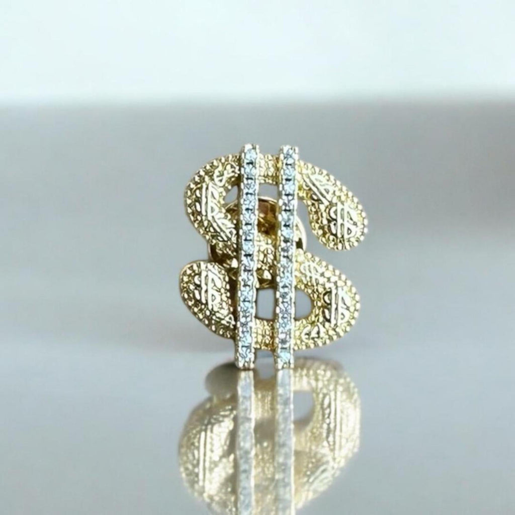 Jakris gold-tone dollar sign brooch featuring a textured surface and a vertical row of sparkling clear crystals.