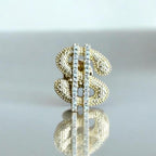 Jakris gold-tone dollar sign brooch featuring a textured surface and a vertical row of sparkling clear crystals.