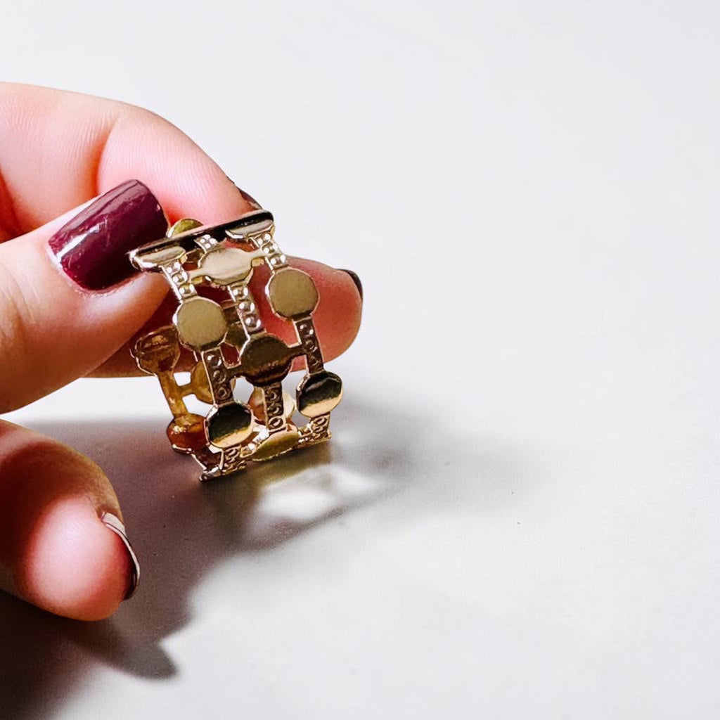 Jakris gold-plated hoop earring featuring a thick, multi-row dotted pattern held between fingers.