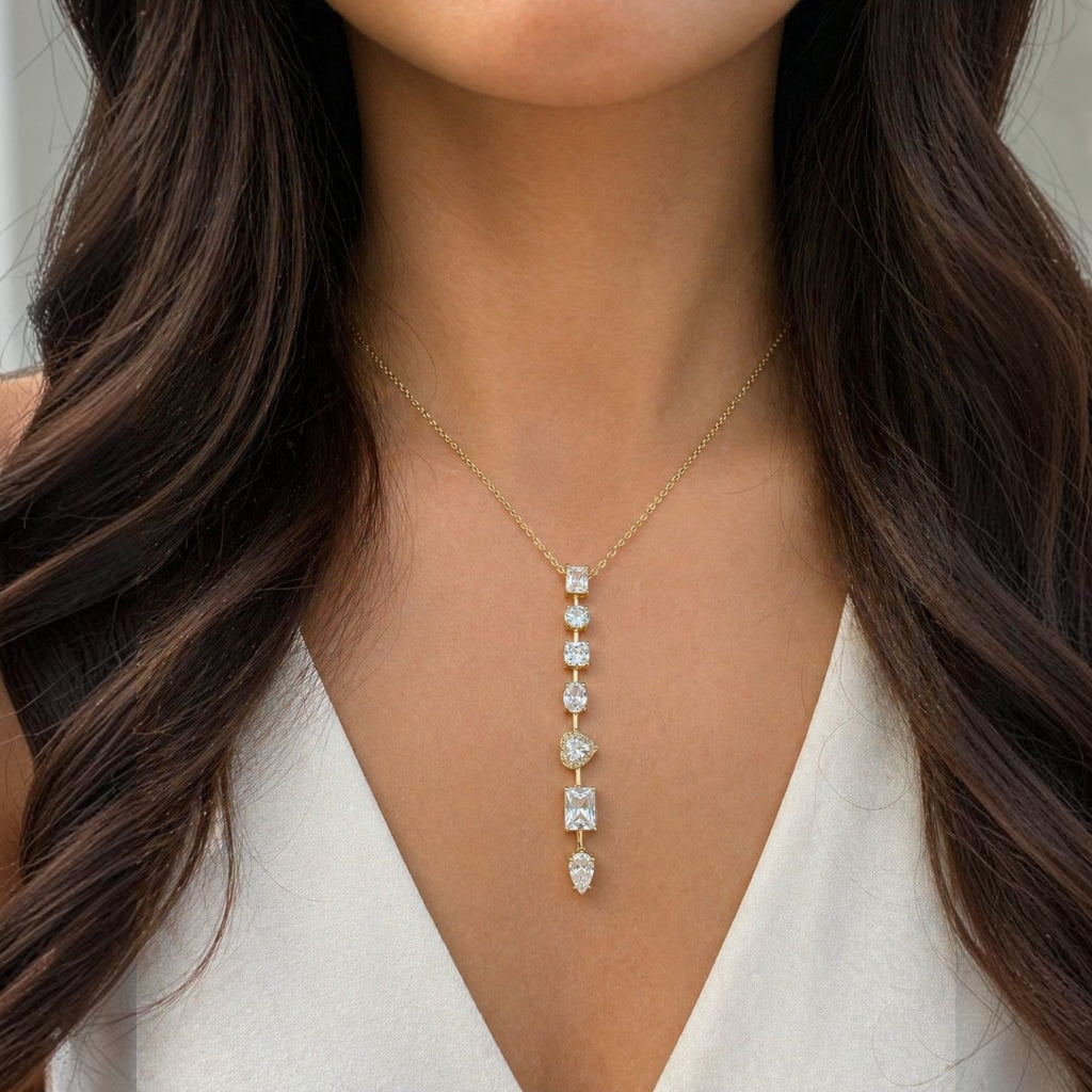 Jakris gold chain necklace featuring a vertical drop of assorted cut clear stones worn on a woman