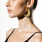Jakris 24k gold plated feather shaped statement earring worn by a model in profile view