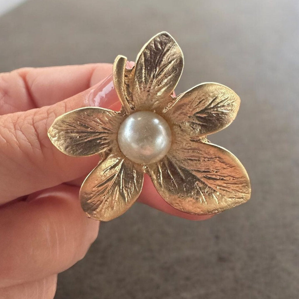 Jakris gold-plated textured flower earring with a central pearl detail held in hand