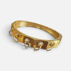 Jakris gold plated geometric bangle bracelet featuring dangling ring charms and a mixed metal silver accent
