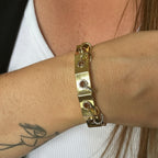 Jakris gold-plated geometric cuff bracelet featuring silver and gold dangling ring details on a woman's wrist