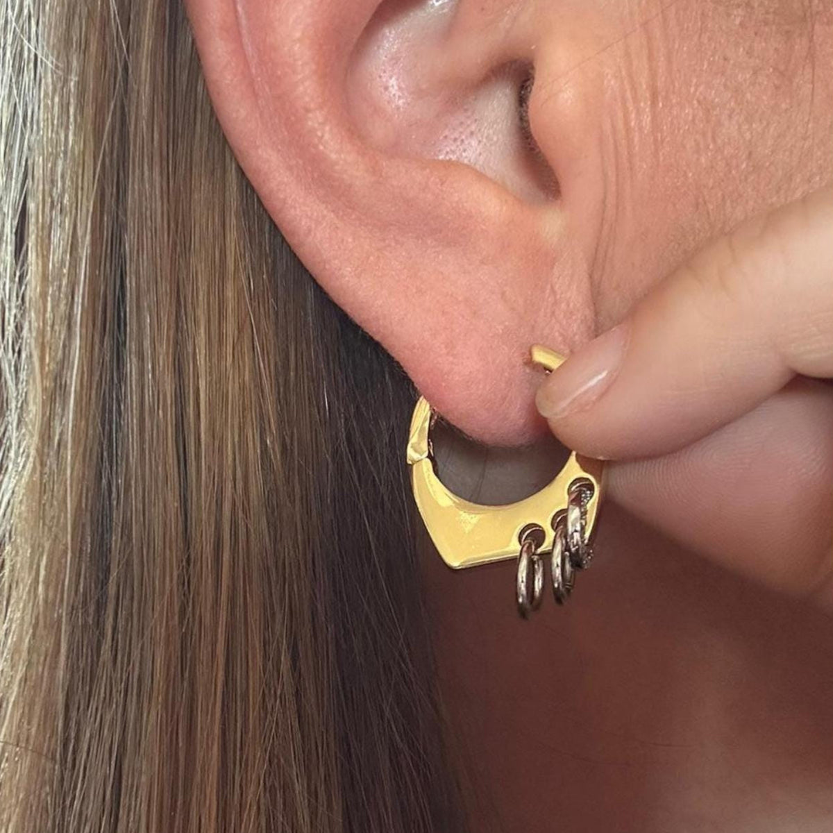 Jakris modern gold-tone hoop earring featuring geometric shapes and small silver-toned ring accents worn on ear