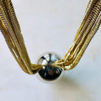Jakris gold-tone multi-strand layered chain necklace featuring a central polished silver-tone ball bead detail