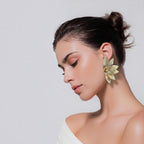 Jakris gold leaf-shaped statement earring with a central floral crystal detail worn by a woman with an updo hairstyle.