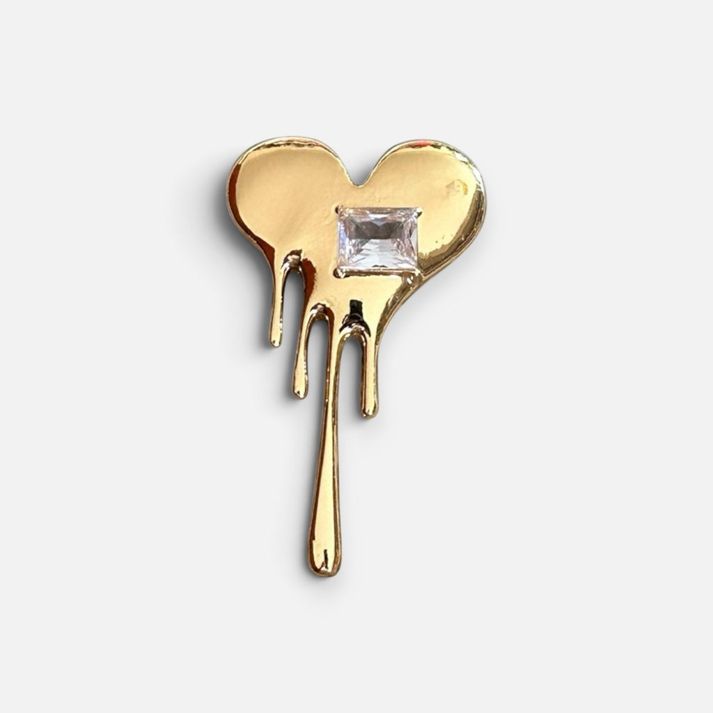 Jakris gold-tone melting heart brooch featuring a central square-cut crystal stone on a white background.