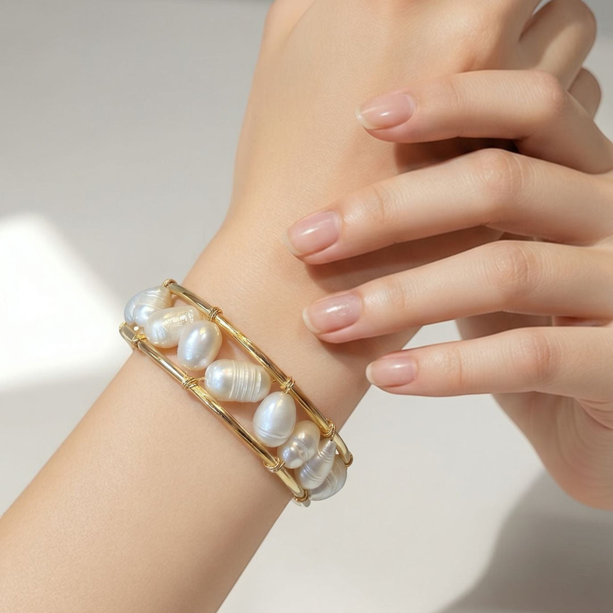 Jakris gold bracelet featuring natural freshwater pearls in a modern open-cuff design worn on a woman's wrist.
