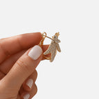 Jakris gold hoop earring featuring a sparkling zircon-encrusted phoenix design held between fingers