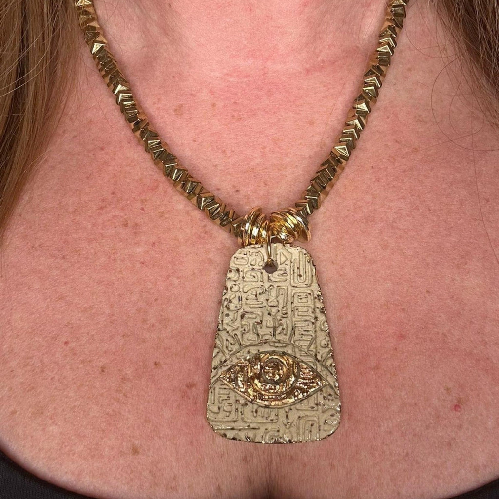 Jakris gold-plated brass necklace featuring a textured pendant with an evil eye motif and geometric beaded chain