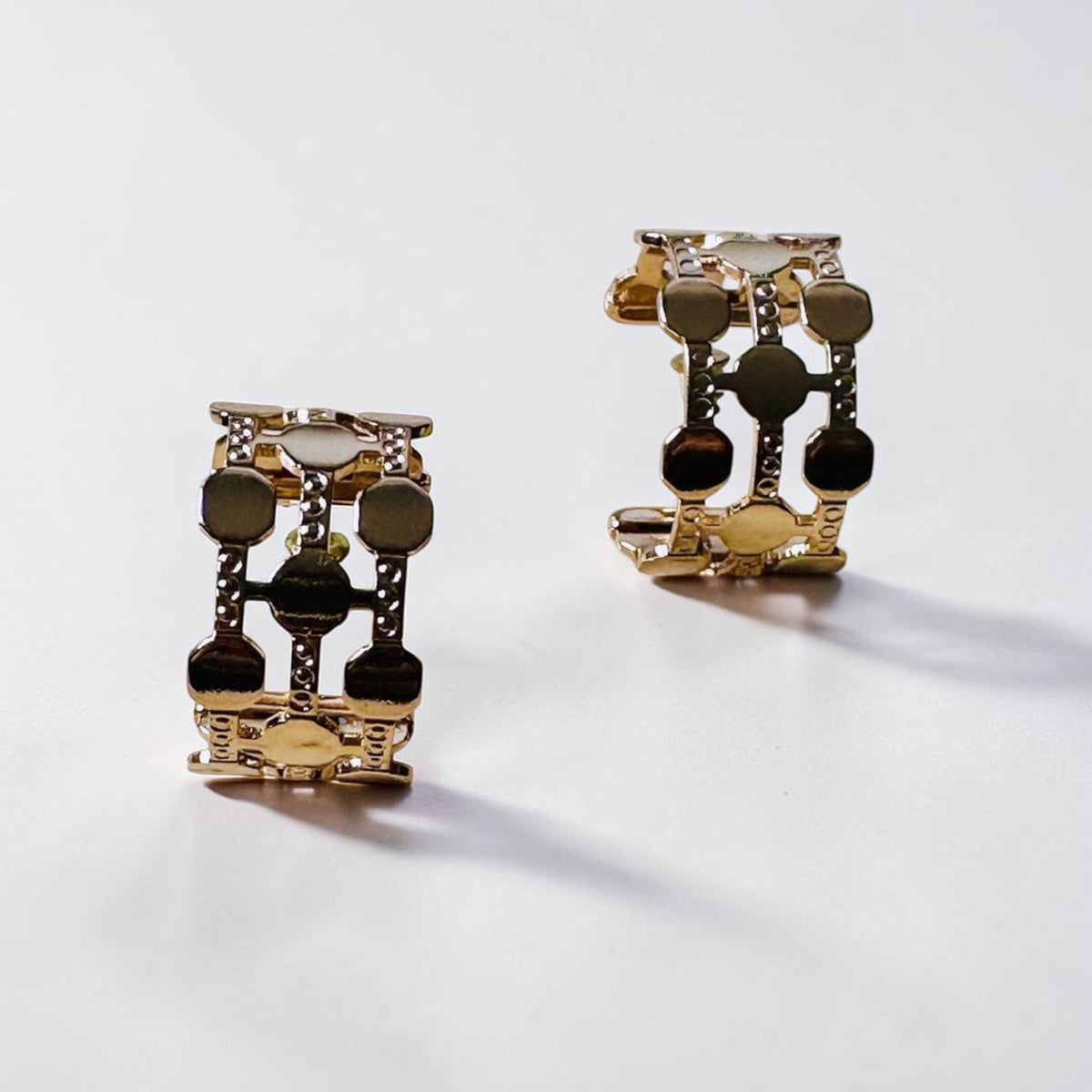 Jakris gold-plated hoop earrings featuring a thick, geometric dotted pattern on a clean white background.