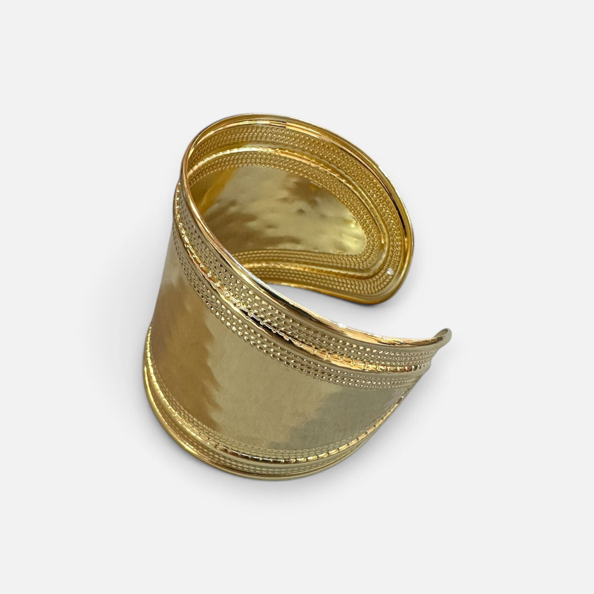 Jakris wide gold-plated brass cuff bracelet with a textured polished finish and adjustable open design.