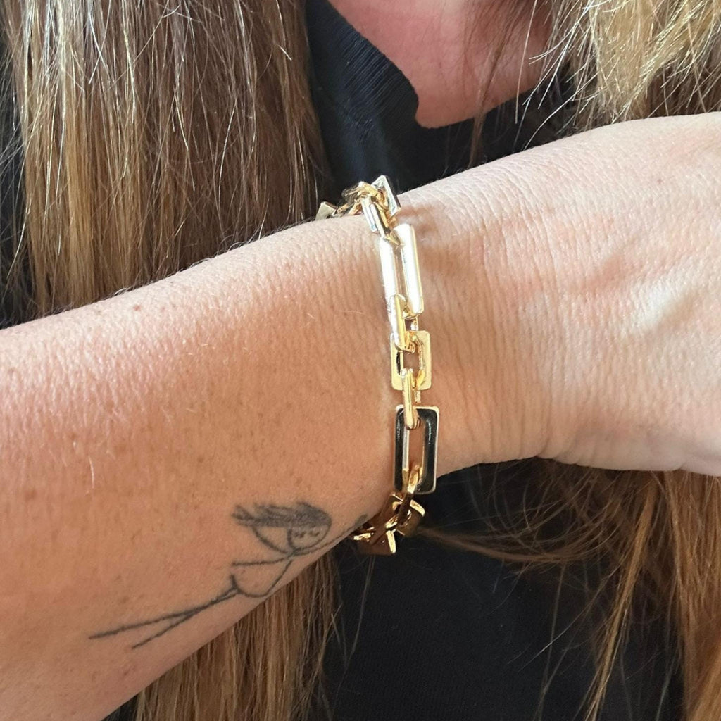 Jakris gold-toned chunky rectangular link chain bracelet worn on a woman's wrist
