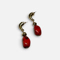 Jakris gold-tone drop earrings featuring bold red stone accents and a modern curved design.