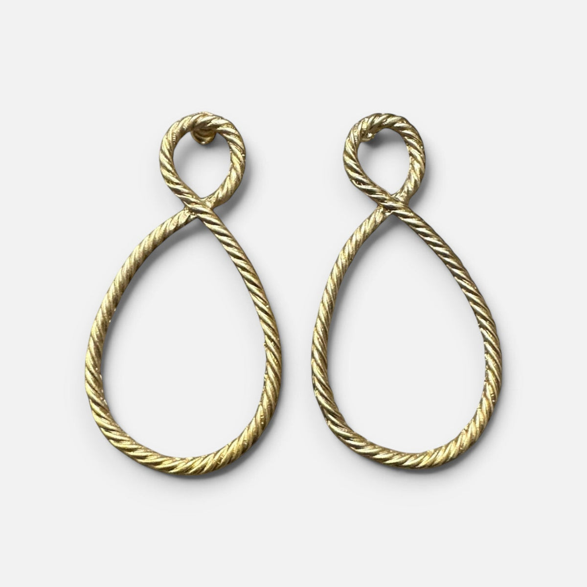 Jakris gold-plated earrings featuring a twisted rope design in a teardrop shape on a white surface.