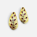 Jakris gold-plated teardrop earrings featuring textured shell-like details and inlaid oval ruby gemstones.