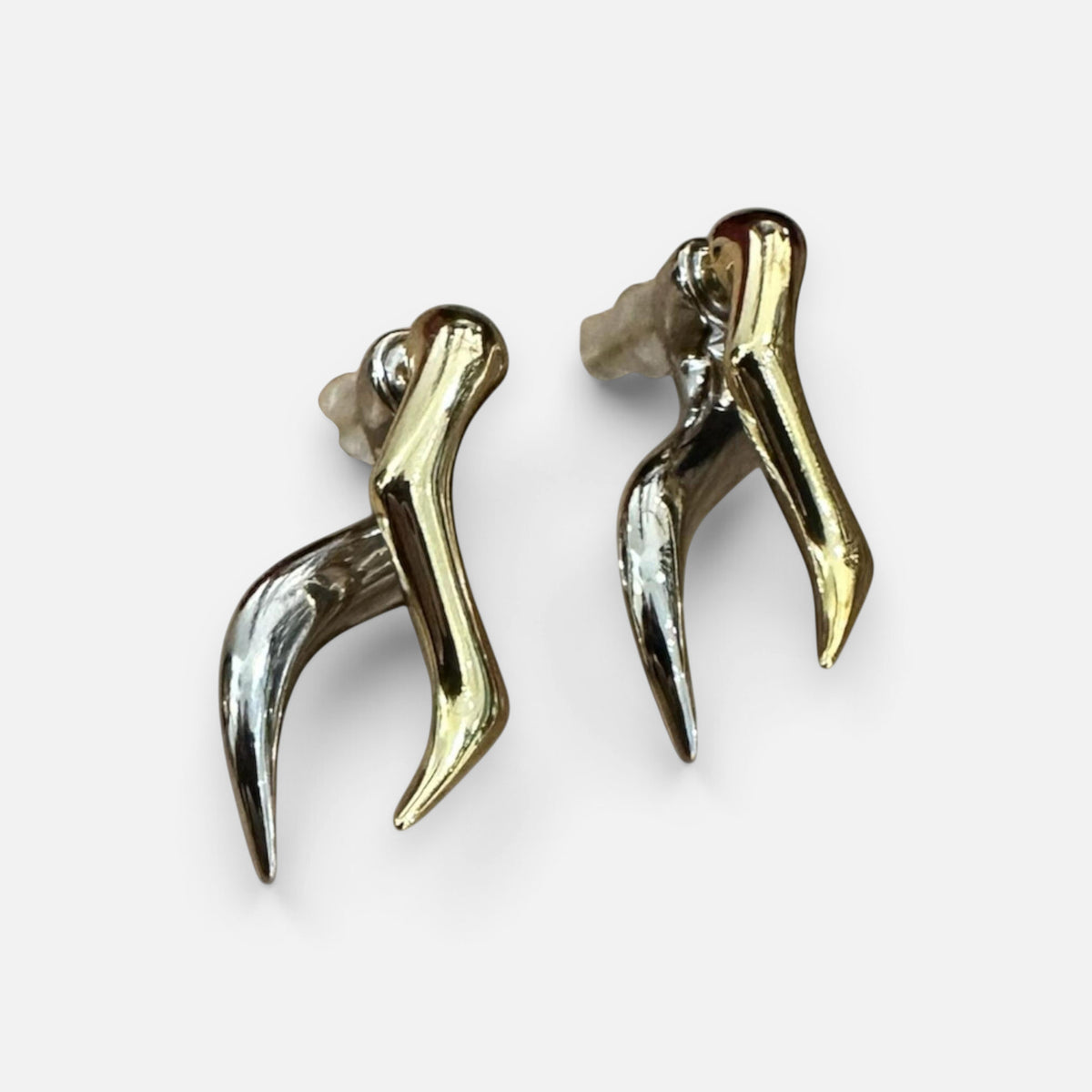Jakris modern abstract earrings featuring a two-tone gold and silver metallic design with a sleek, curved shape.
