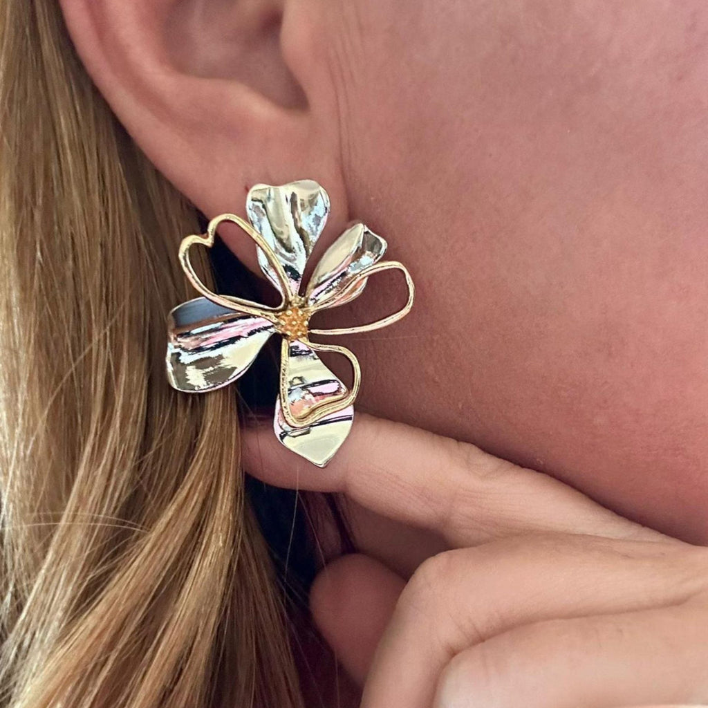 Jakris mixed metal flower earrings in gold and silver tones worn on an earlobe