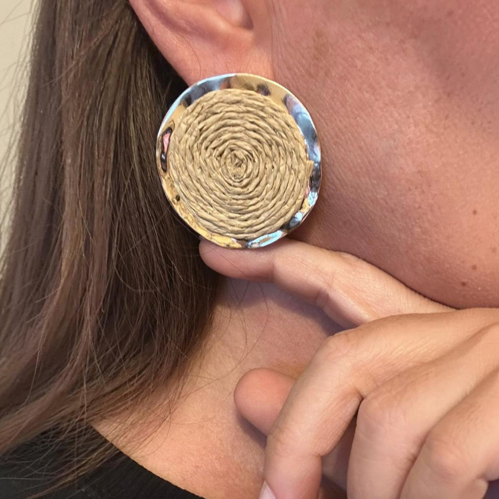 Jakris round earrings featuring a natural woven straw center and a polished gold-plated brass frame on a model.