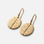 Jakris gold textured disc earrings with a vertical line of small sparkling stones on a marble surface.