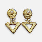 Jakris gold triangle drop earrings with textured geometric surfaces and central pearl accents