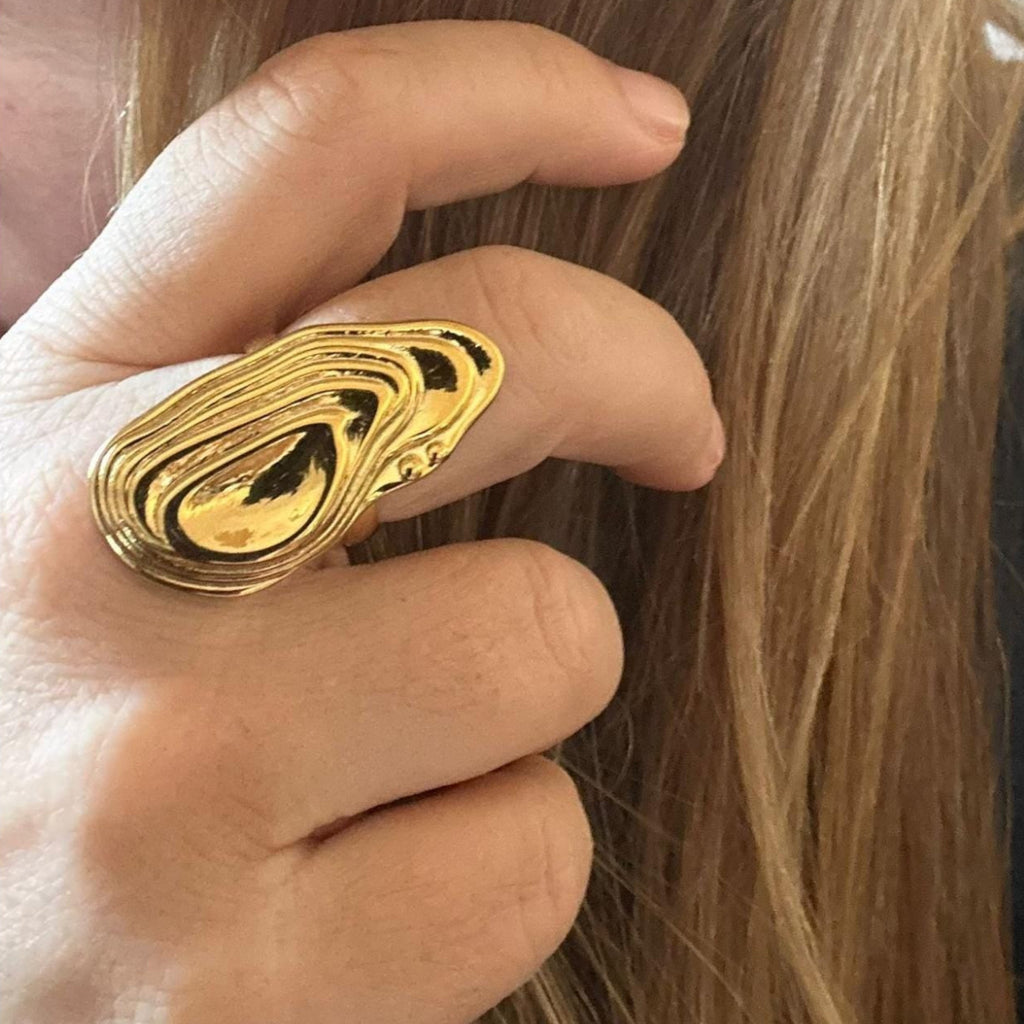 Jakris gold adjustable ring with a sculptural, abstract topographic design worn on a finger.