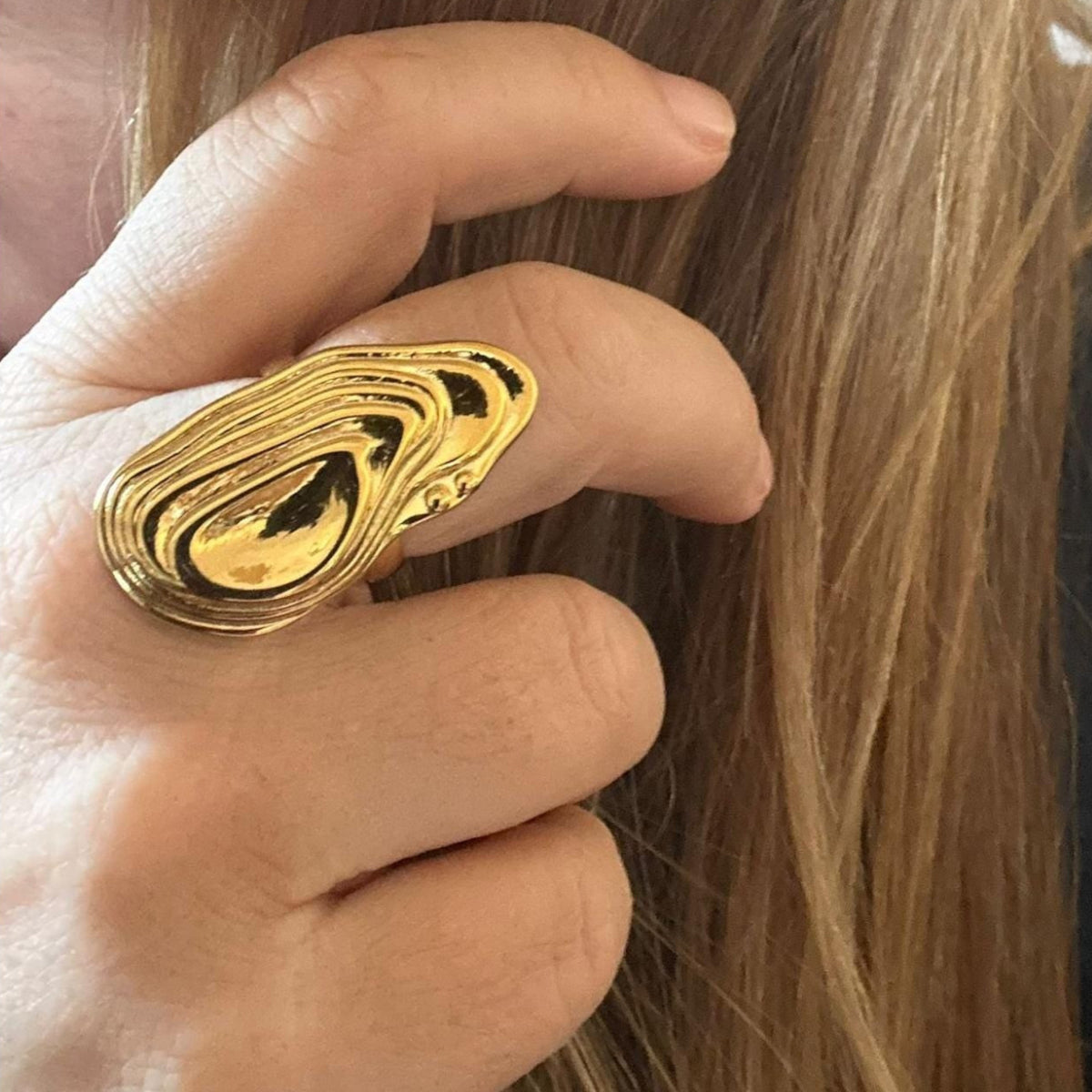 Jakris gold adjustable ring with a sculptural, abstract topographic design worn on a finger.