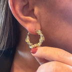 Jakris gold-tone twisted textured hoop earring worn on an earlobe for a stylish party look