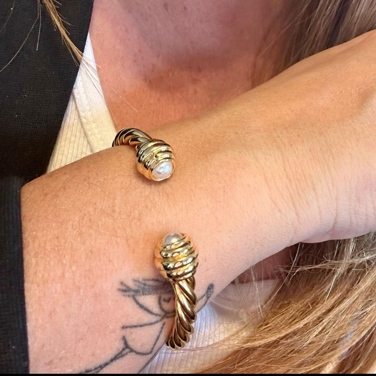 Jakris gold twisted cuff bracelet featuring elegant pearl accents on both ends worn on a wrist