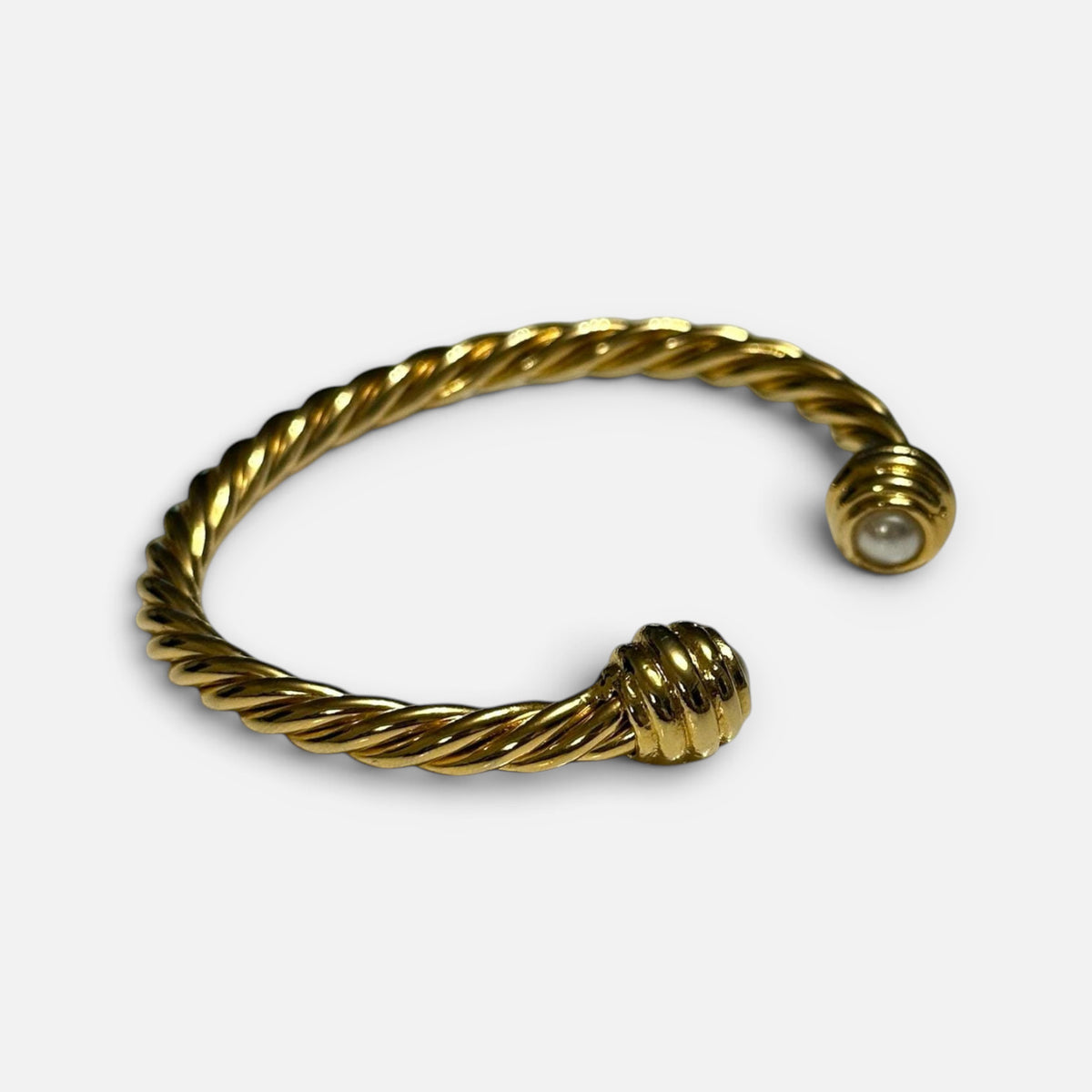 Jakris gold twisted cuff bracelet featuring a delicate pearl accent at the open end