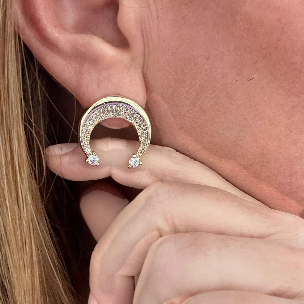 Jakris gold crescent moon earring adorned with sparkling zircon stones worn on an earlobe