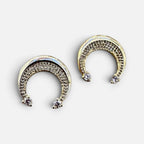 Jakris gold crescent moon earrings adorned with sparkling zircon stones on a reflective surface.
