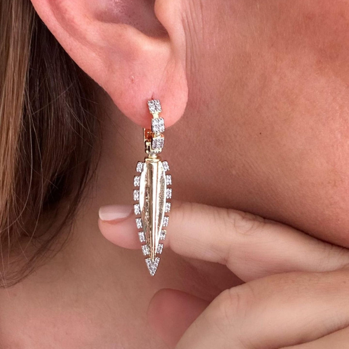 Jakris gold-plated long drop earring featuring sparkling zircon stones worn on an earlobe