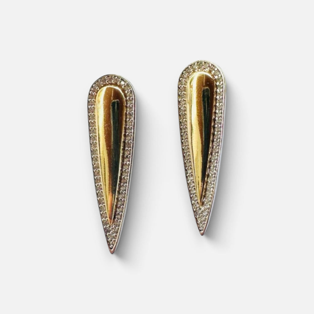 Jakris gold teardrop earrings with silver edges and sparkling zircon stone accents on a reflective surface