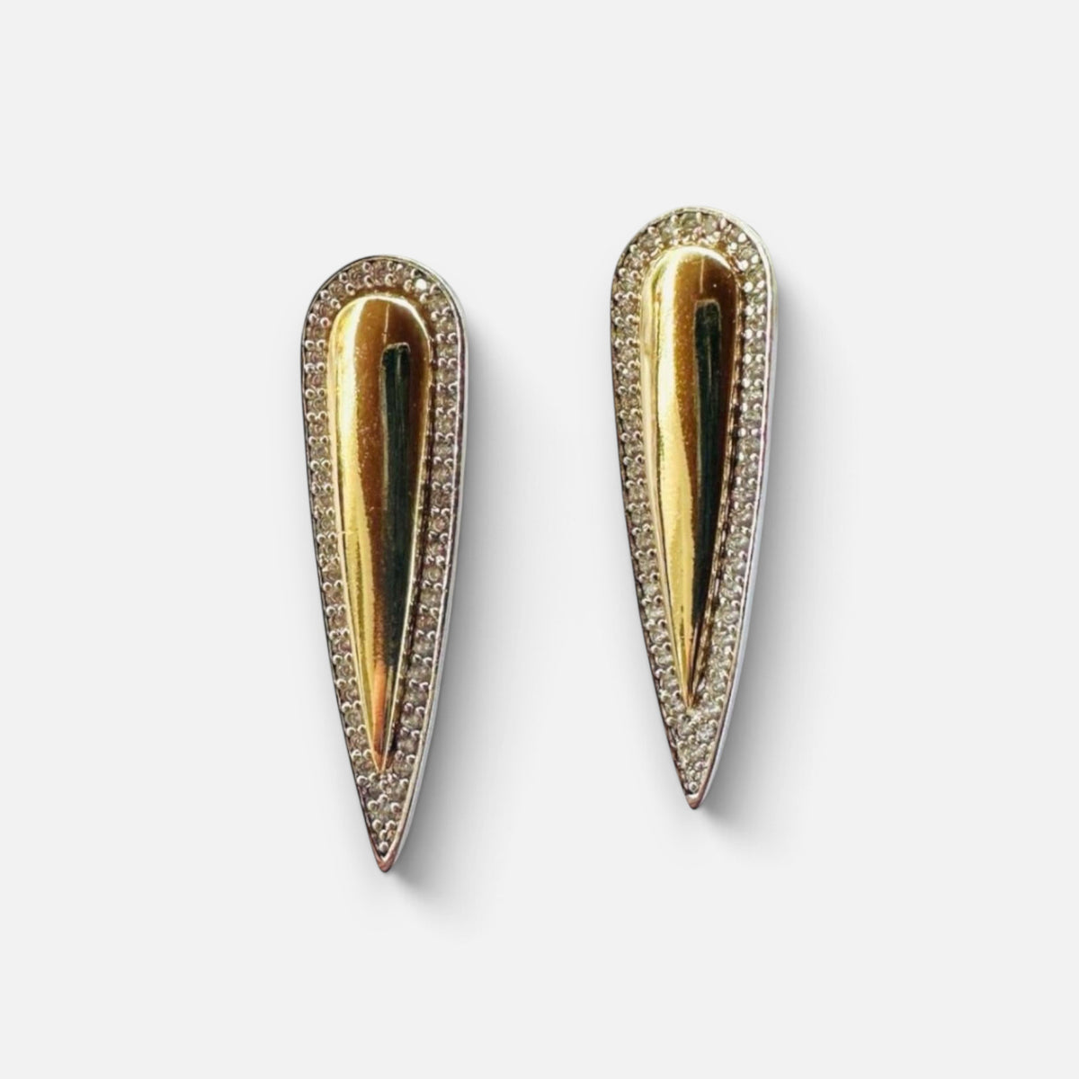 Jakris gold teardrop earrings with silver edges and sparkling zircon stone accents on a reflective surface
