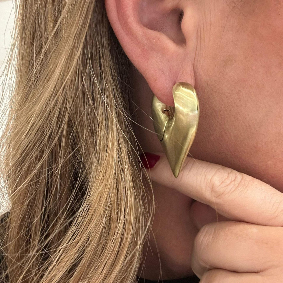 Jakris Joyce Maçaro design heart-shaped brass earring with white gold rhodium plating worn on a woman's ear