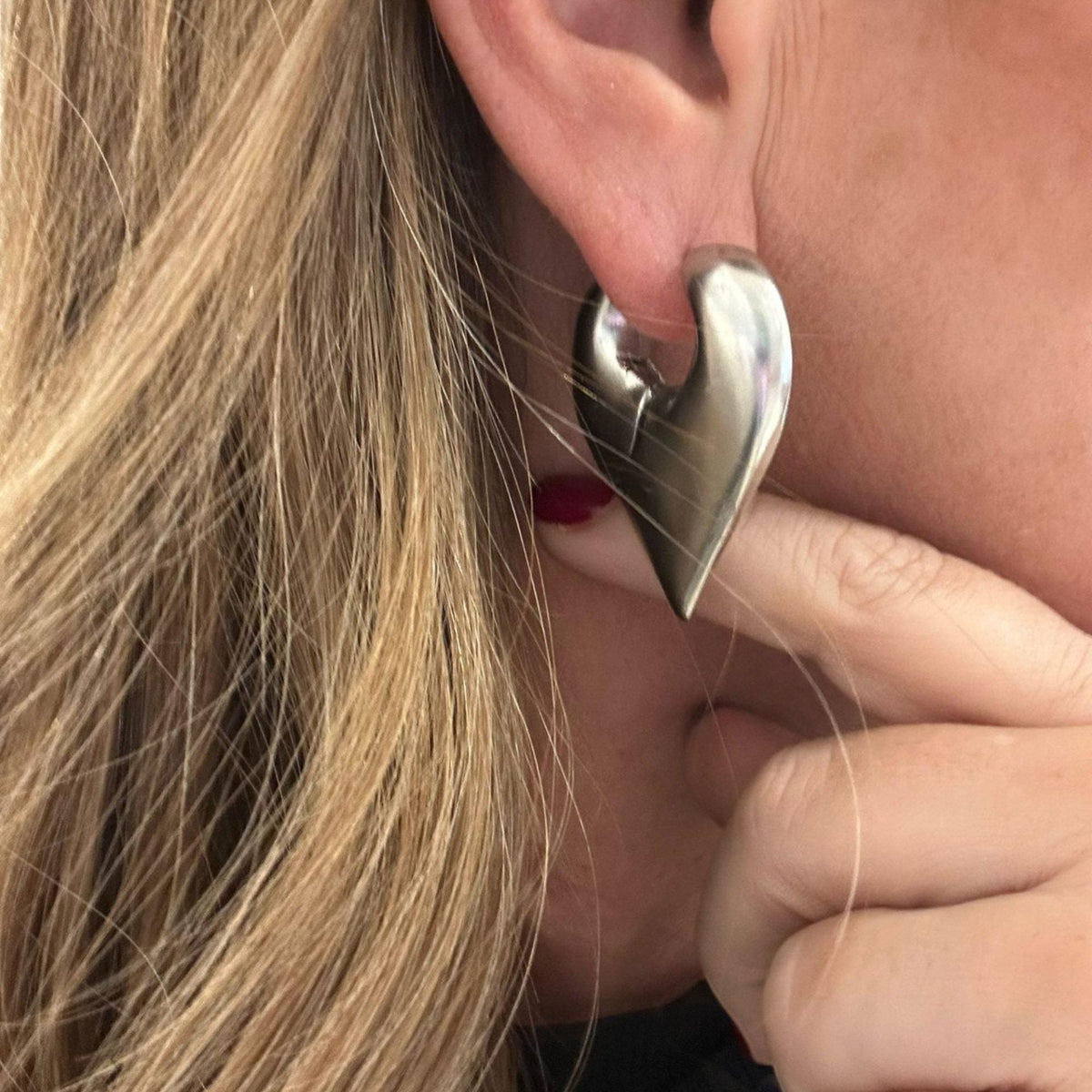 Jakris Joyce Maçaro design heart-shaped earring in white gold rhodium-plated brass worn on a woman's ear