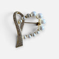 Jakris heart-shaped brooch featuring lustrous white pearls and sparkling gold-tone crystals on a metallic frame.