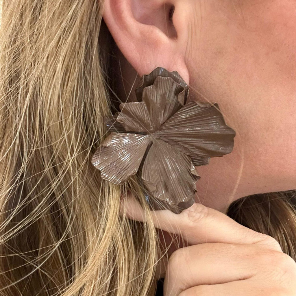 Jakris large brown flower-shaped statement earring worn on a woman's ear with textured petal details