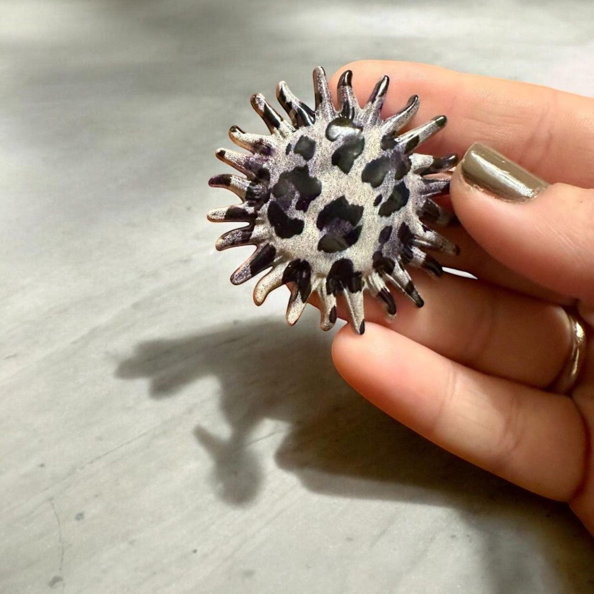 Jakris round earring with leopard and zebra print and a serrated edge held in a hand