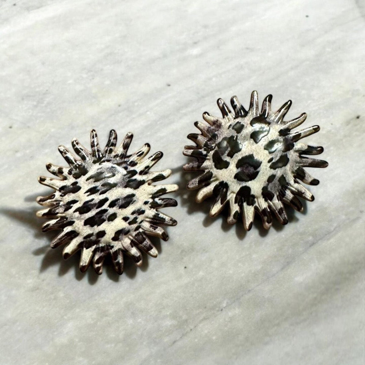 Jakris round earrings featuring a leopard and zebra print pattern with a textured, spiked edge design.
