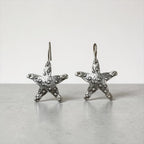 Jakris Maris silver-plated brass starfish earrings with a textured surface and minimalist hook design.