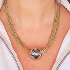 Jakris multi-strand gold-tone chain necklace featuring a central polished silver-tone spherical bead charm