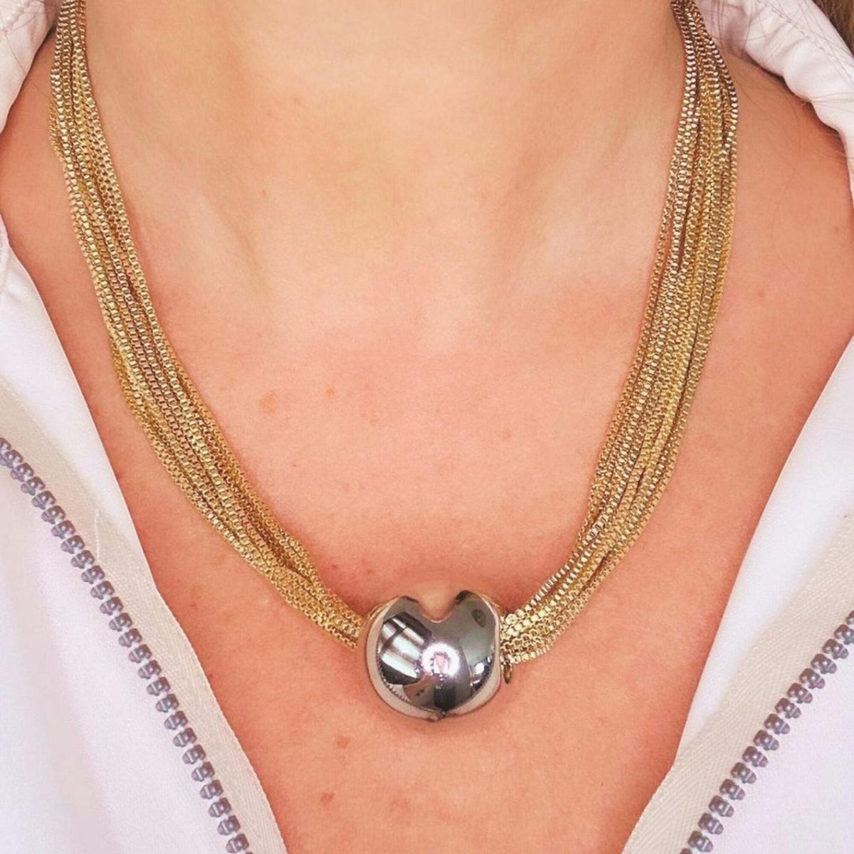 Jakris multi-strand gold-tone chain necklace featuring a central polished silver-tone spherical bead charm