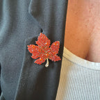Jakris sparkling orange maple leaf brooch pinned to a black blazer lapel