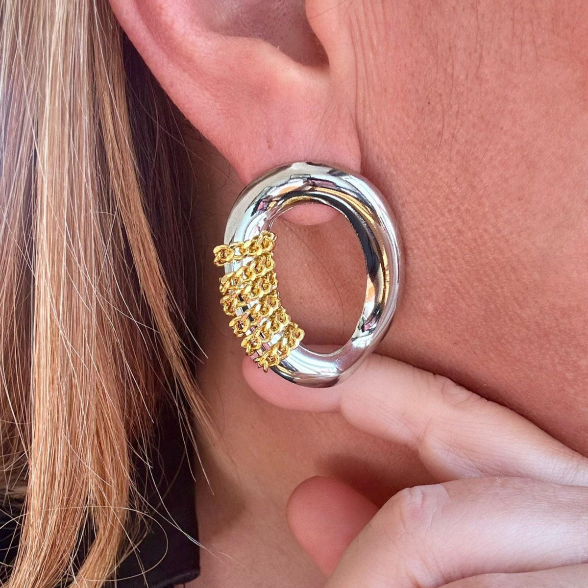 Jakris oval silver earring featuring a modern gold chain detail worn on an ear