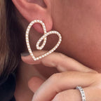 Jakris elegant heart-shaped bridal earrings featuring delicate white pearls worn on a model