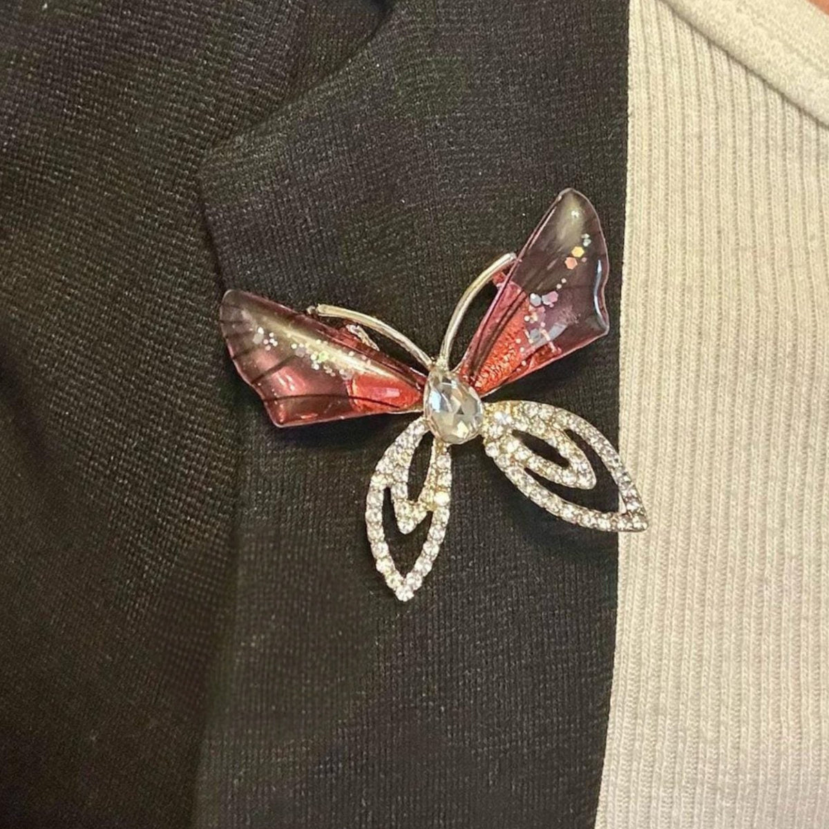 Jakris elegant butterfly brooch featuring pink translucent wings and sparkling crystal accents on a black blazer